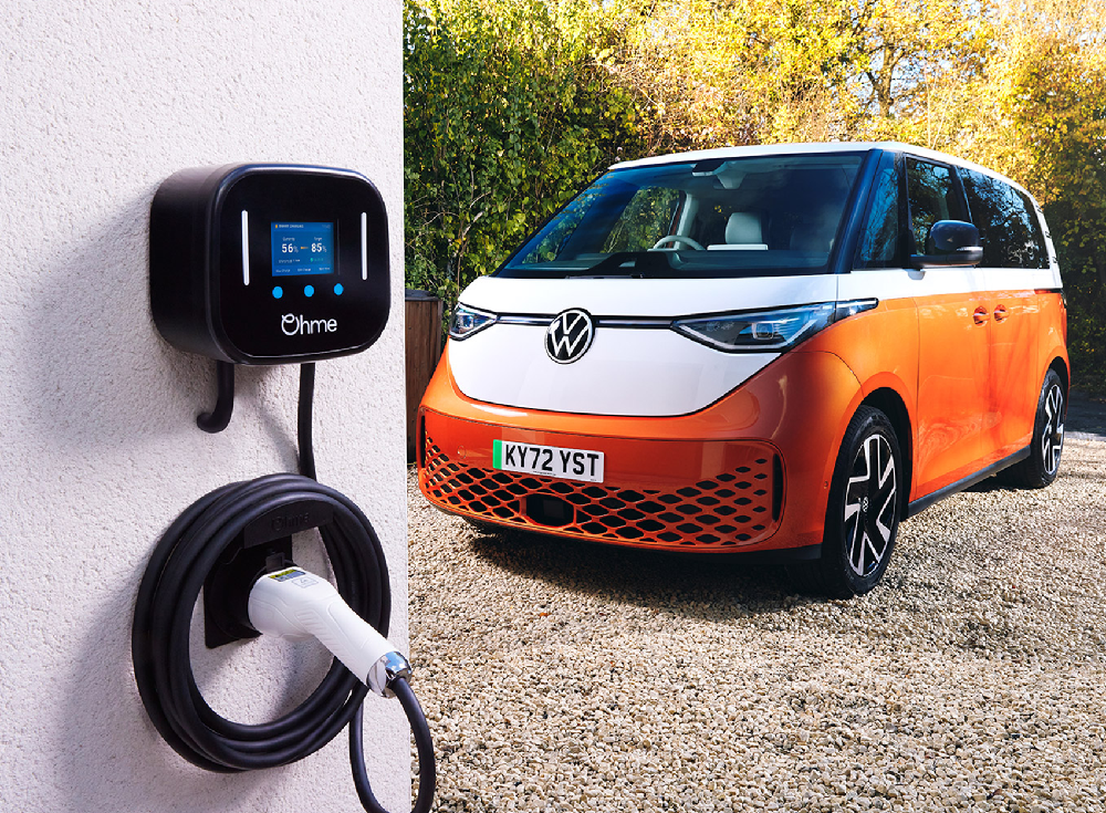 Ohme Home Pro smart EV charger mounted on wall with cable neatly stored, parked Volkswagen ID. Buzz in background